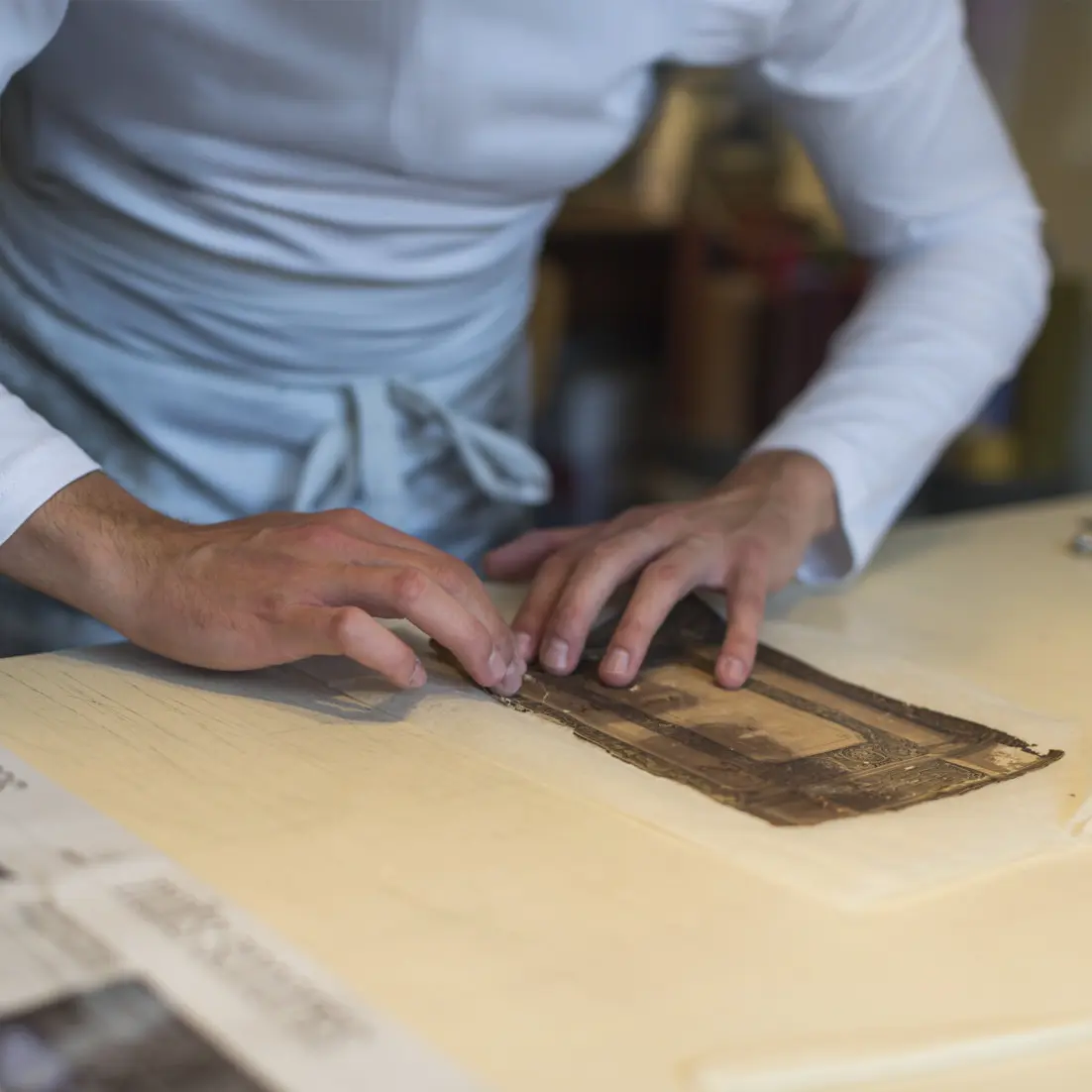 Mains d’artisan restaurateur de livres anciens manipulant avec précision une couverture en cuir décorée, à l’Atelier Reliure Paris
