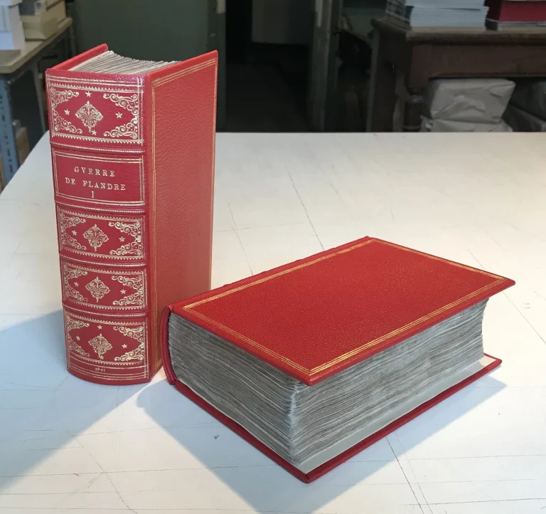 Livre ancien Histoire de la Guerre de Flandre restauré et relié en cuir rouge avec dorure, travail artisanal de l’Atelier Reliure Paris